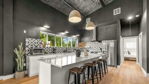 A modern kitchen with a large island, bar stools, and pendant lighting.