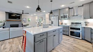 A modern kitchen with grey cabinets, stainless steel appliances, and a central island.