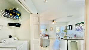 Una cocina moderna con lavavajillas incorporado, una zona de comedor con mesa redonda y un área de lavandería con lavadora.