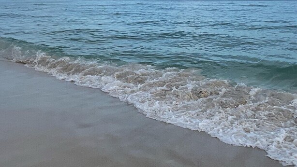 Una playa con olas suaves lamiendo la orilla.