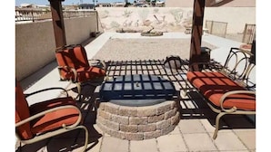 A patio area with outdoor seating, a fire pit, and a view of a desert landscape. - Custom 4 bdrm with Granny Suite and Infinity Pool (Bullhead City)