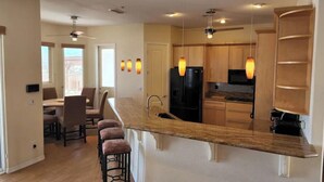 A modern kitchen with a large island, wooden cabinets, and pendant lighting. - Custom 4 bdrm with Granny Suite and Infinity Pool (Bullhead City)