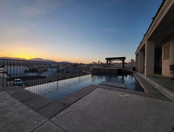 Relax by the serene pool surrounded by a tranquil landscape and shaded pergola.