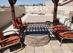 A patio area with outdoor seating, a fire pit, and a view of a desert landscape.