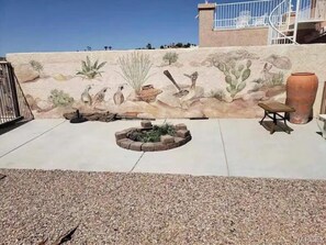 Relax in a serene outdoor space surrounded by desert-inspired artwork and a tranquil atmosphere.