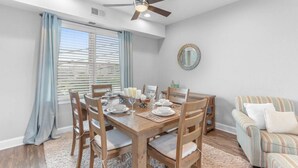 A dining area with a wooden table, chairs, and a ceiling fan.