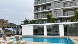 En modern byggnad med en pool på taket, ett utomhusgym och utsikt över stadsbilden.