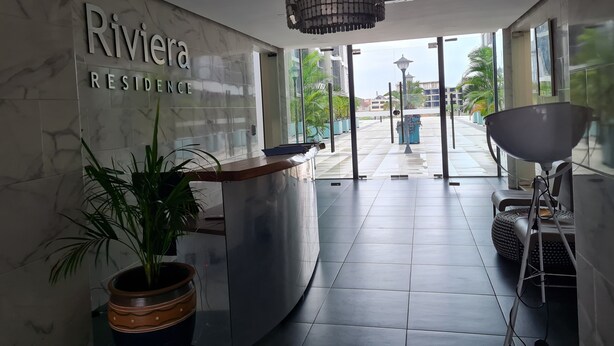 En modern hotellobby med en vägg av marmor, en receptionsdisk, en krukväxt och en stor kristallkrona.