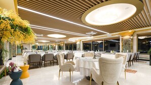 Un comedor amplio con mesas y sillas redondas, ventanas grandes y un diseño de techo moderno.