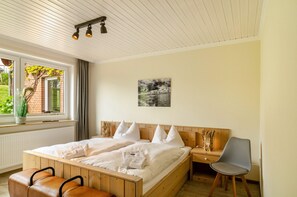 Un dormitorio con una cama grande, mesitas de noche, una silla, un ventanal con cortinas y un cuadro en la pared.
