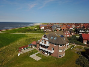 Vista aérea de una zona residencial con casas, una playa y cielo despejado.