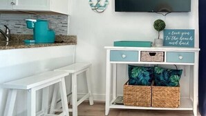 A kitchen with white cabinets, a teal countertop, and a white bar stool. - Seawatch Resort - King Bed (Myrtle Beach)