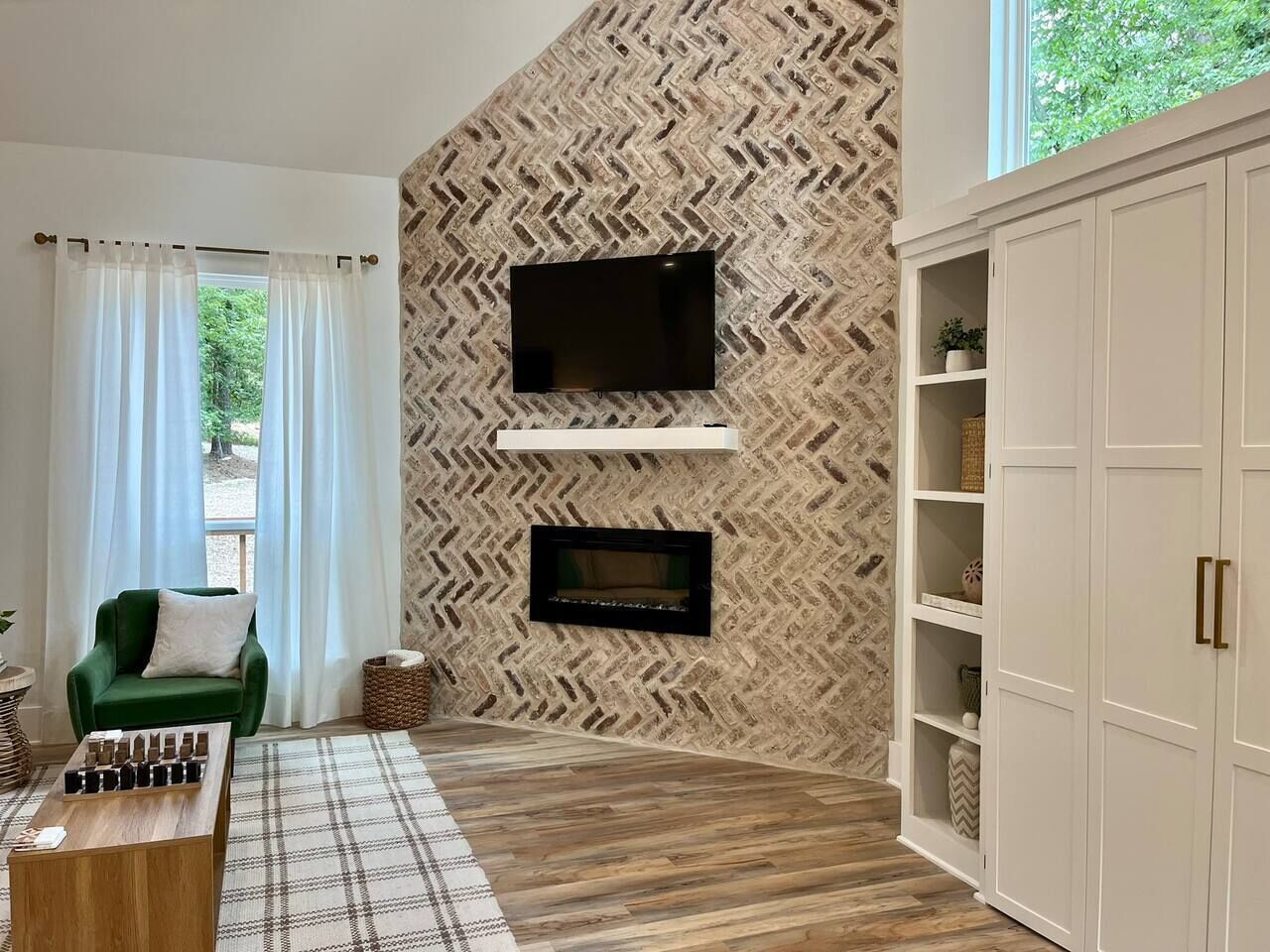 Una sala de estar moderna con un muro de patrón estampada de serreta, un televisor de pantalla plana, una chimenea, un sillón verde y una mesa de centro de madera.