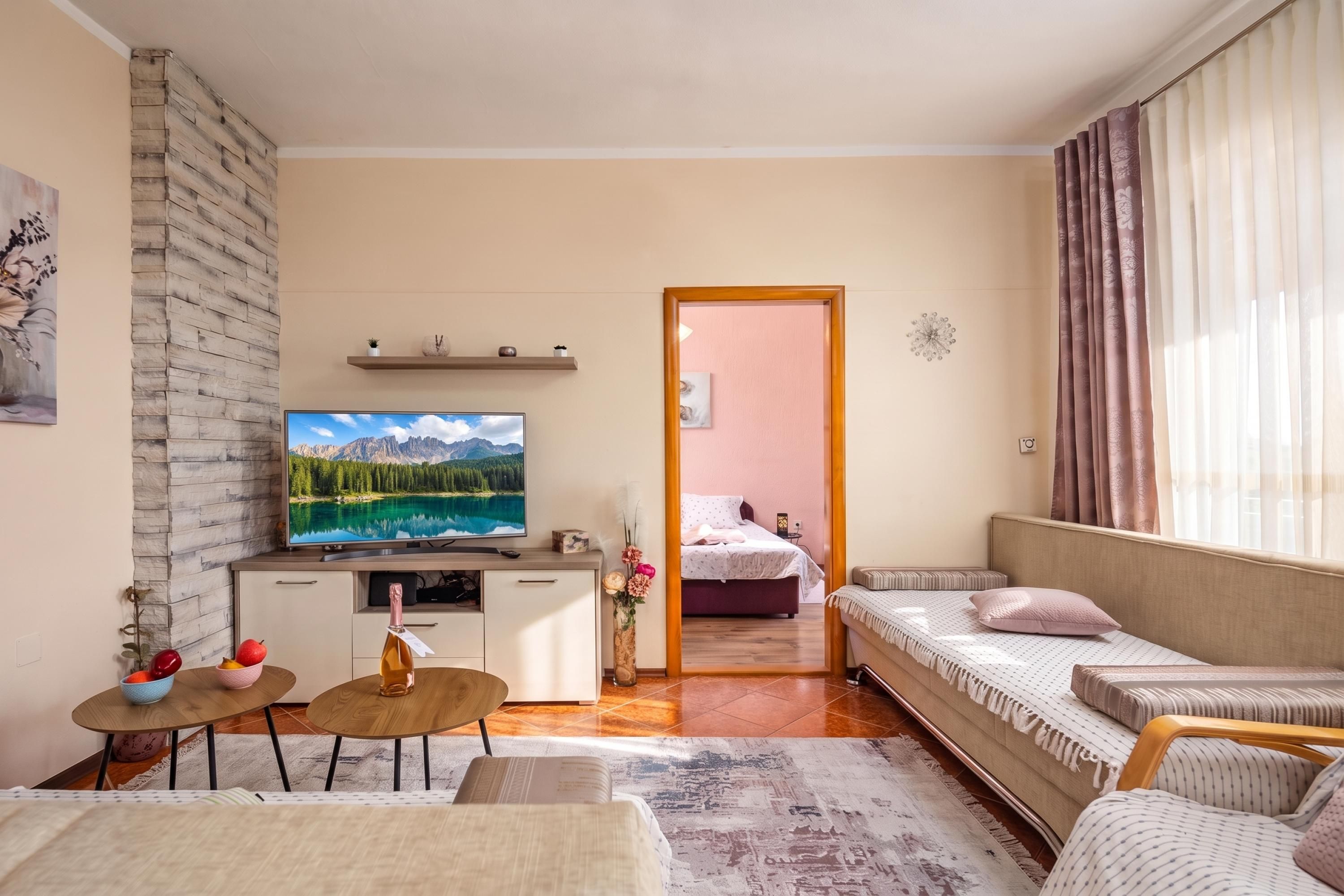 Una sala moderna con un televisor de pantalla plana, un sofá, una mesa de comedor y una cama al fondo.