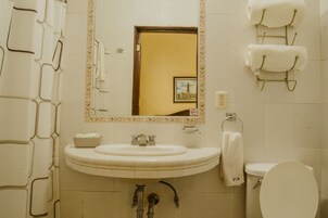 A bathroom with a sink, mirror, toilet, and towel rack.