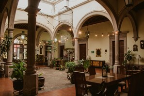 A spacious courtyard with arches, potted plants, and a wooden table and chairs. - Hotel Posada San Agustin (Durango)