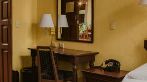 A hotel room with a wooden desk, a chair, a telephone, and a mirror on the wall. - Hotel Posada San Agustin (Durango)