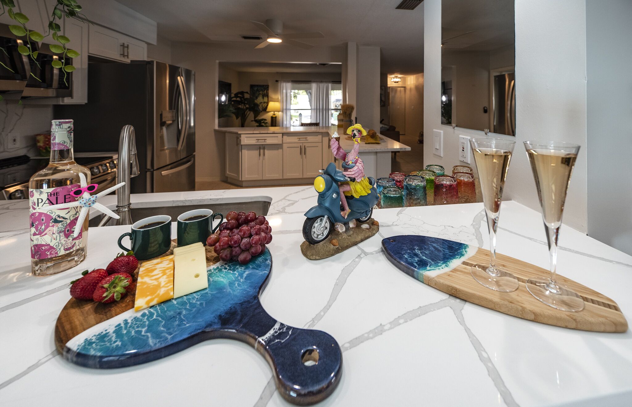 Uma bancada de cozinha com diversos alimentos, uma scooter decorativa e uma taça de champanhe.
