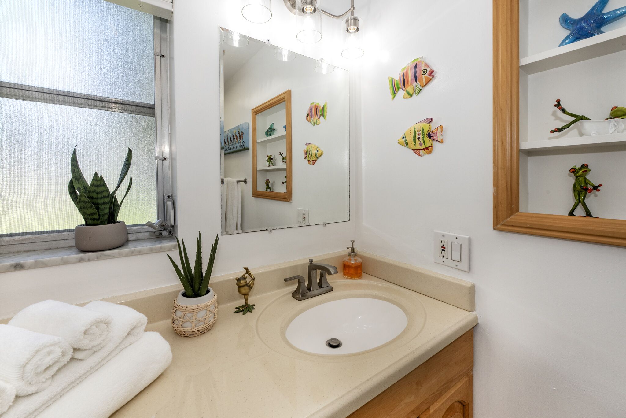 Une salle de bain avec un lavabo, un miroir et des autocollants décoratifs représentant des poissons sur le mur.