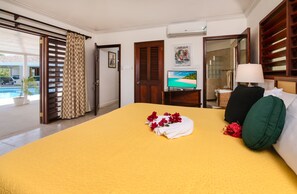 A hotel room with a bed, a desk with a computer, a bathroom, and a view of the outdoors. - Ultra-private villa on the fairway at world-famous Tryall Golf Club. (Sandy Bay)