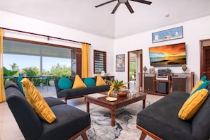 A spacious living area with a sofa, chairs, a coffee table, and a television. - Ultra-private villa on the fairway at world-famous Tryall Golf Club. (Sandy Bay)