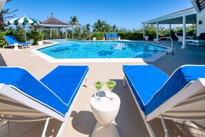 A pool area with lounge chairs, a small table with drinks, and a gazebo in the background. - Ultra-private villa on the fairway at world-famous Tryall Golf Club. (Sandy Bay)