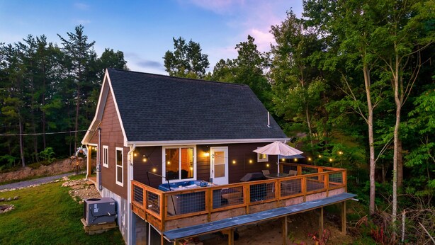 A cabin with a deck, outdoor seating, and a covered porch area.