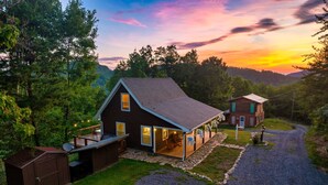 A two-story house with a porch, a garage, and a gravel driveway.