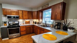 A modern kitchen with wooden cabinets, a stainless steel stove, and a sink. - Dog-Friendly Boyne City Home | Game Room, Near Lake Charlevoix + Downtown (Boyne City)