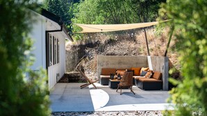 Eine Terrasse im Freien mit einer Couch, einem Holzstuhl und einer Hängematte.