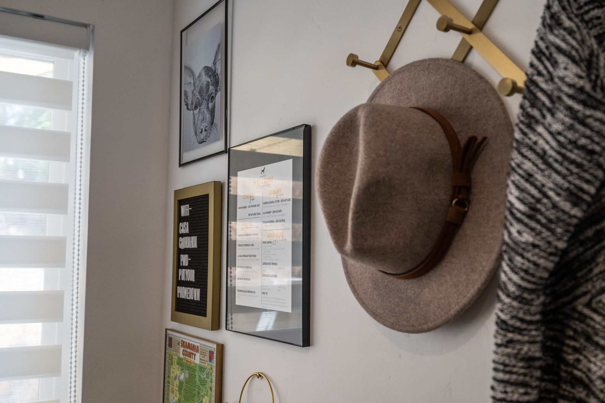 A wall with framed items including a map, a welcome sign, and a framed list of names.