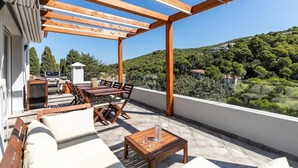 A covered outdoor patio with a table and chairs, a sofa, and a small table with a glass. - Villa Casa Nuestra with Private Pool, Garden & Wi-Fi (Begur)