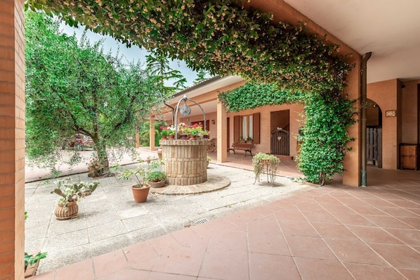 A courtyard with a fountain, potted plants, and a bench.
