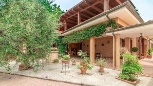 A covered outdoor area with brick walls, potted plants, and a pergola. - Villa Rosso Corbezzolo (Carassai)