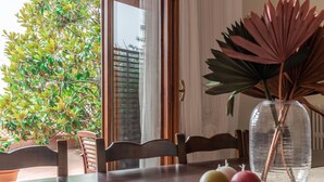 A dining table with chairs, a vase with dried plants, and a woven basket with apples. - Villa Rosso Corbezzolo (Carassai)