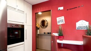 A kitchen with white cabinets, a black oven, and a wooden door leading to a hallway. - Holiday Apartment "El Refugio" with Wi-Fi & Terrace (Jerez de la Frontera)