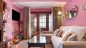 A living room with a sofa, a glass coffee table, a TV, and a decorative lantern. - Holiday Apartment "El Refugio" with Wi-Fi & Terrace (Jerez de la Frontera)
