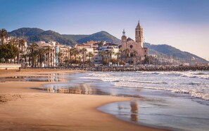 Une ville côtière qui se distingue par son église imposante, sa plage de sable et une montagne qui se profile à l’arrière-plan.