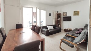 A spacious living area with a wooden dining table, black leather sofa, and a patterned sofa. - Apartment MariBeach Sitges with Terrace, A/C & Wi-Fi (Sitges)