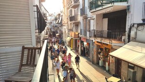 A crowded street with people walking, shops, and buildings with balconies. - Apartment MariBeach Sitges with Terrace, A/C & Wi-Fi (Sitges)