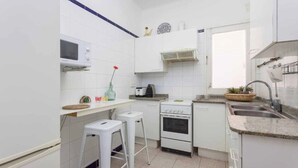 A compact kitchen with white cabinets, a microwave, a stove, and a sink. - Apartment MariBeach Sitges with Terrace, A/C & Wi-Fi (Sitges)