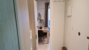 Un couloir avec une porte, une petite table avec une chaise et une plante en pot.