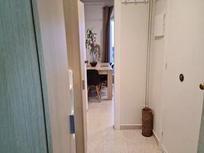 A hallway with a door, a small table with a chair, and a potted plant. - Pet-Friendly Apartment MariBeach2 Sitges with A/C & Wi-Fi (sitges)