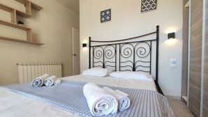 Un lit bien fait, avec des serviettes pliées, un radiateur et un luminaire fixé au mur.