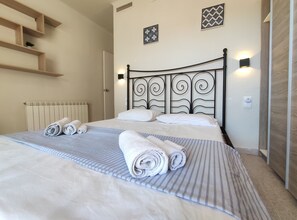 A neatly made bed with rolled towels, a radiator, and a wall-mounted light fixture. - Pet-Friendly Apartment MariBeach2 Sitges with A/C & Wi-Fi (sitges)