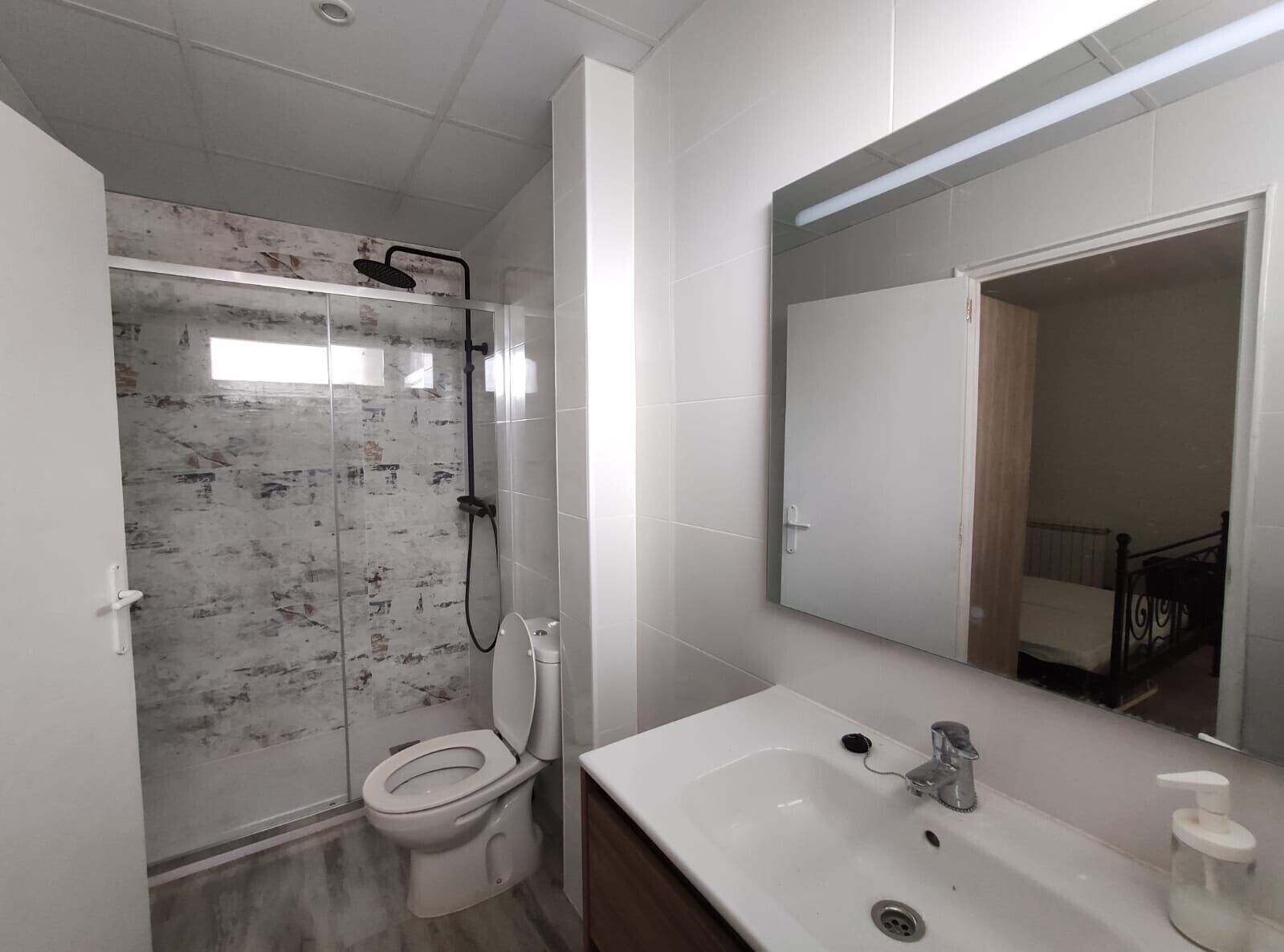A bathroom with a shower, toilet, sink, and mirror.