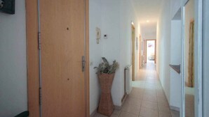 A hallway with a wooden door, a potted plant, and a tiled floor. - Holiday Home 'Maribeach3' with Private Terrace, Wi-Fi and Air Conditioning (Sitges)