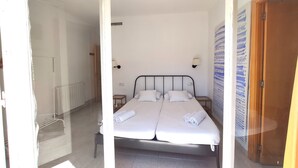 A double bed with white linens, a bedside table, a wall-mounted lamp, and a radiator. - Holiday Home 'Maribeach3' with Private Terrace, Wi-Fi and Air Conditioning (Sitges)