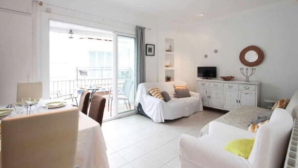 A bright room with a bed, a sofa, a TV, and a balcony. - Holiday Home 'Maribeach3' with Private Terrace, Wi-Fi and Air Conditioning (Sitges)