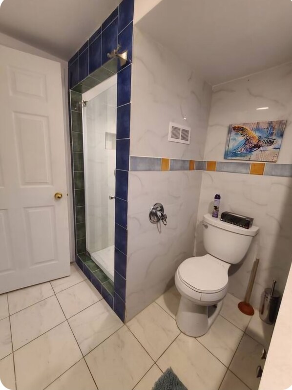 A bathroom with a shower, toilet, and a painting on the wall. - The cozy nook in waterloo (Waterloo)